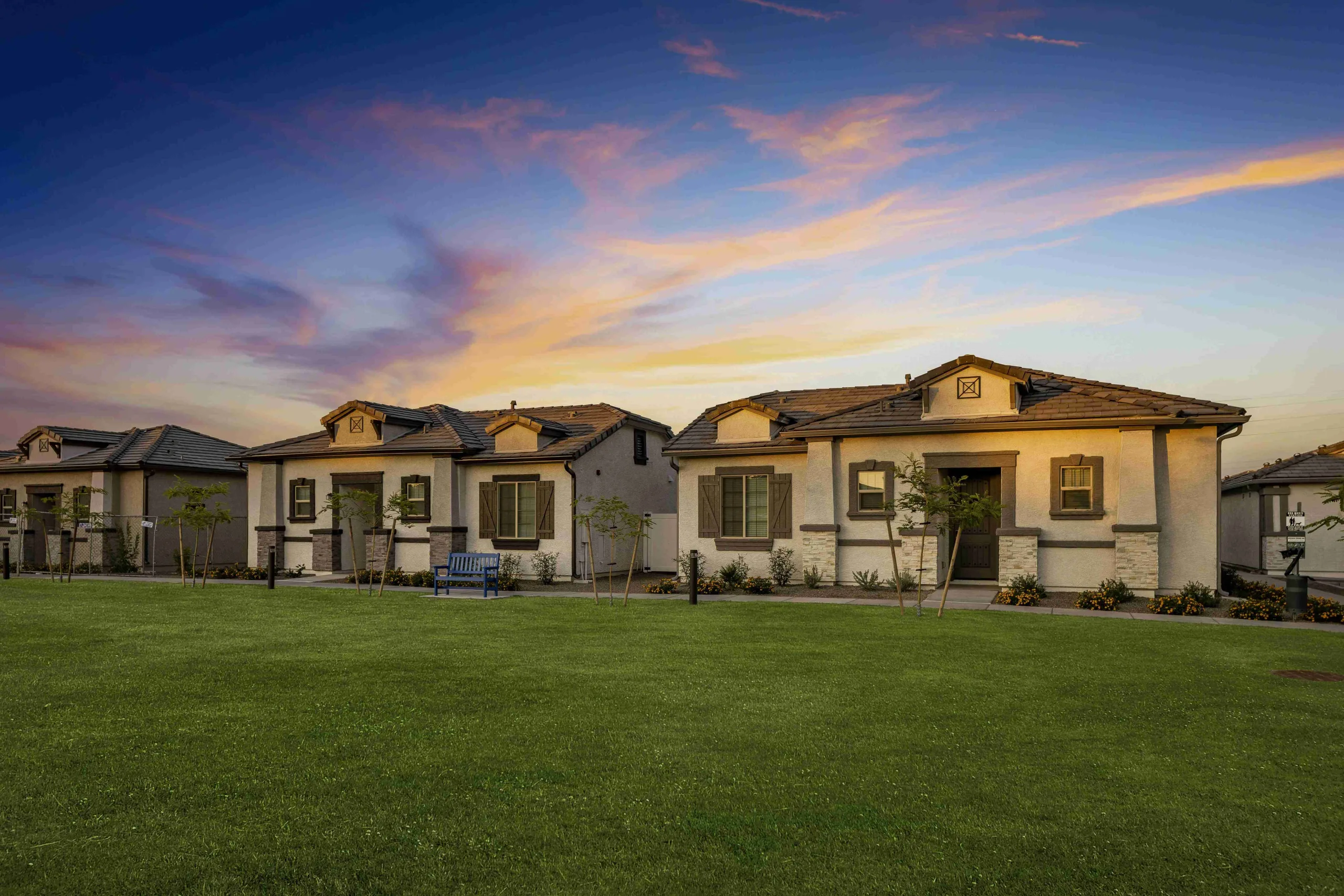 Front of homes during sunset facing the community lawn and pool.